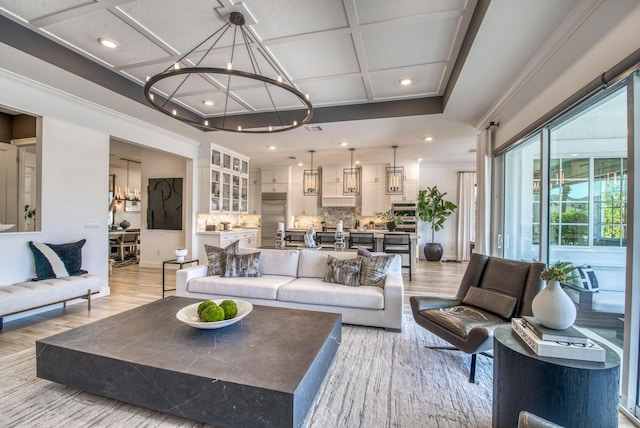 living room with light wood-type flooring, a notable chandelier, and coffered ceiling