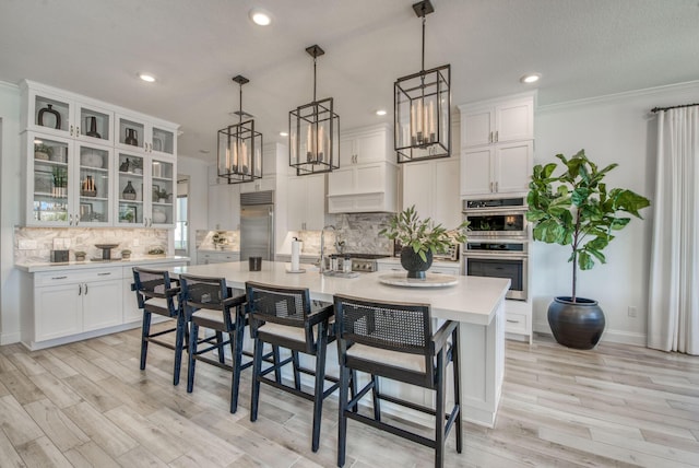 kitchen featuring white cabinets, a kitchen bar, appliances with stainless steel finishes, and a center island with sink