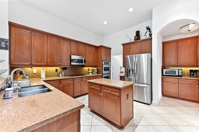 kitchen featuring tasteful backsplash, a kitchen island, appliances with stainless steel finishes, light tile patterned flooring, and sink