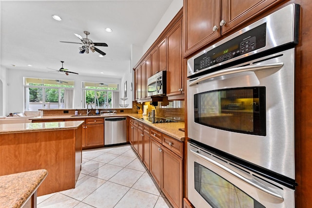 kitchen featuring stainless steel appliances, kitchen peninsula, light tile patterned floors, light stone counters, and sink