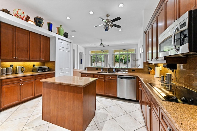 kitchen with stainless steel appliances, sink, a center island, light tile patterned flooring, and tasteful backsplash