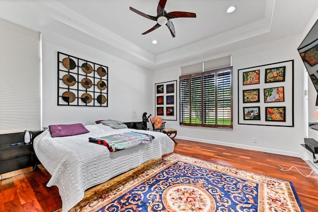 bedroom featuring ornamental molding, a raised ceiling, ceiling fan, and wood-type flooring