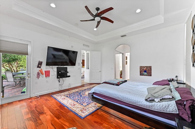 bedroom featuring wood-type flooring, crown molding, ceiling fan, a tray ceiling, and access to outside