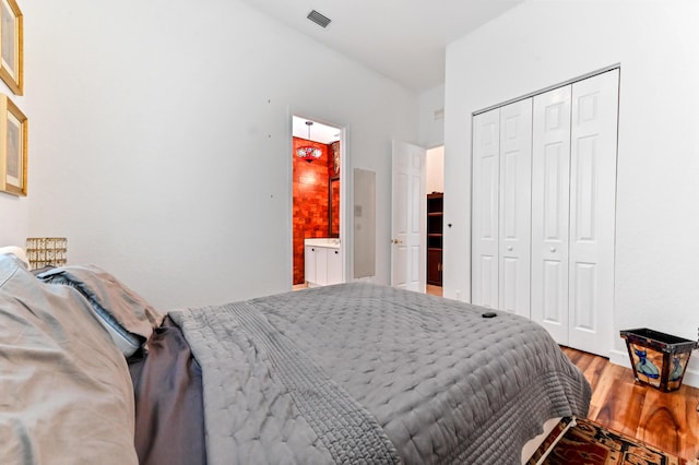 bedroom with ensuite bathroom, a closet, and hardwood / wood-style flooring