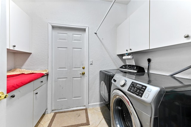 laundry area featuring cabinets, washing machine and clothes dryer, and light tile patterned floors