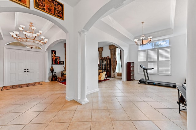 foyer with an inviting chandelier, decorative columns, light tile patterned flooring, a tray ceiling, and crown molding