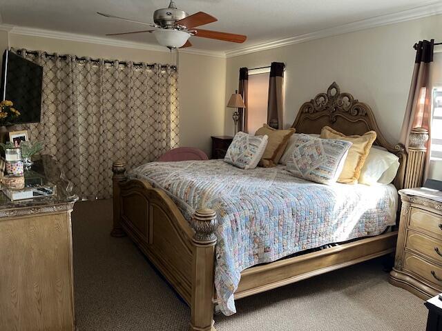 carpeted bedroom featuring ceiling fan and ornamental molding