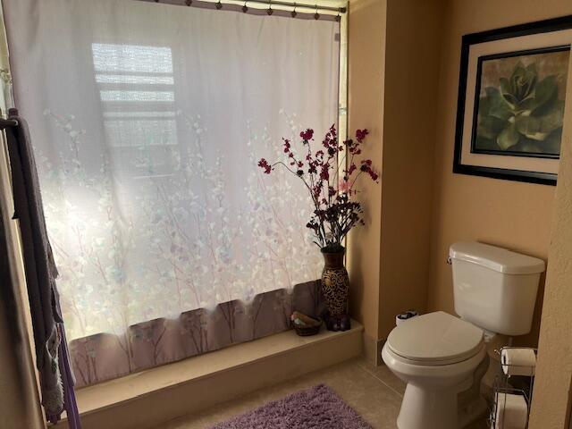 bathroom with tile patterned flooring, curtained shower, and toilet