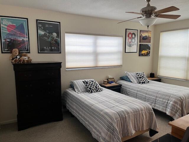 carpeted bedroom featuring multiple windows and ceiling fan