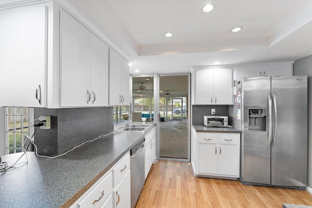 kitchen with decorative backsplash, a tray ceiling, light hardwood / wood-style flooring, appliances with stainless steel finishes, and white cabinets