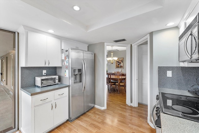 kitchen with backsplash, white cabinetry, light hardwood / wood-style flooring, and stainless steel appliances