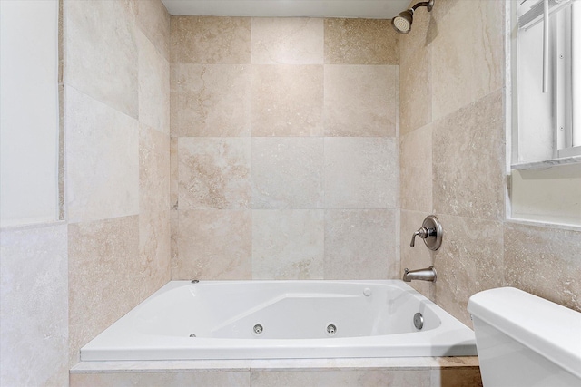 bathroom with toilet, tiled shower / bath, and tile walls