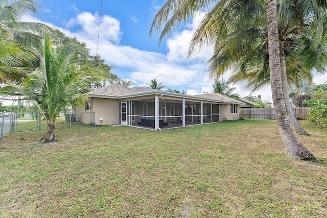 back of property with a sunroom and a lawn