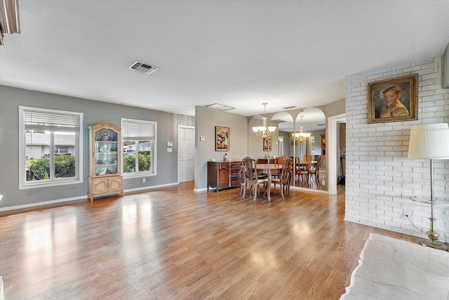 dining room with a textured ceiling, wood-type flooring, and a notable chandelier