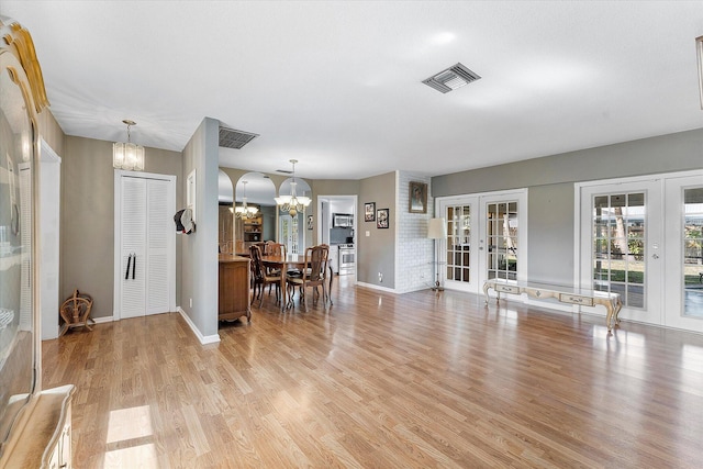 living room with light wood-type flooring, a chandelier, and french doors