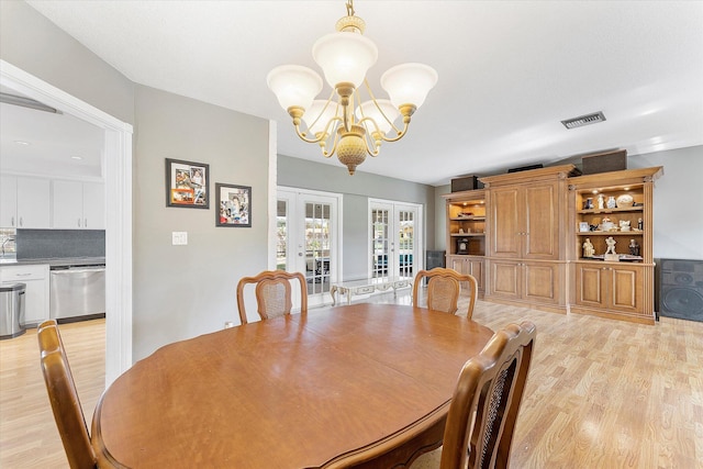 dining area with french doors, a chandelier, and light hardwood / wood-style flooring