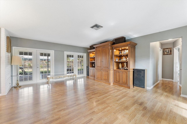 unfurnished living room with french doors and light wood-type flooring