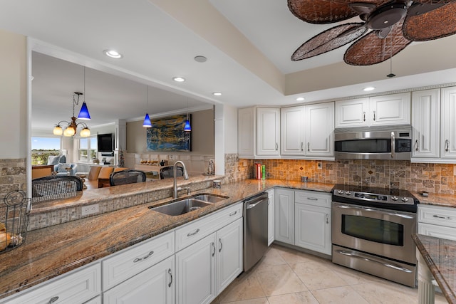 kitchen with stainless steel appliances, sink, white cabinets, dark stone countertops, and ceiling fan