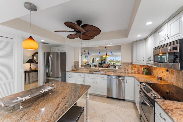 kitchen featuring white cabinets, a raised ceiling, appliances with stainless steel finishes, and pendant lighting