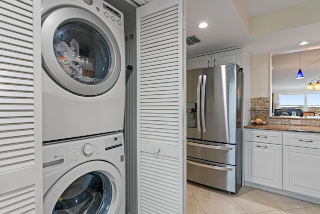 laundry area featuring stacked washer and dryer and light tile patterned flooring