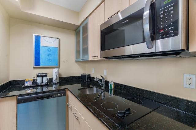 kitchen featuring dark stone countertops, sink, light brown cabinetry, and appliances with stainless steel finishes