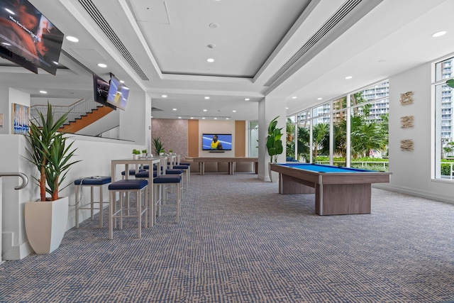 game room featuring a tray ceiling, dark carpet, a healthy amount of sunlight, and pool table