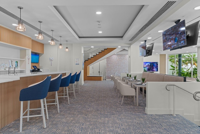 bar featuring built in features, a raised ceiling, and hanging light fixtures