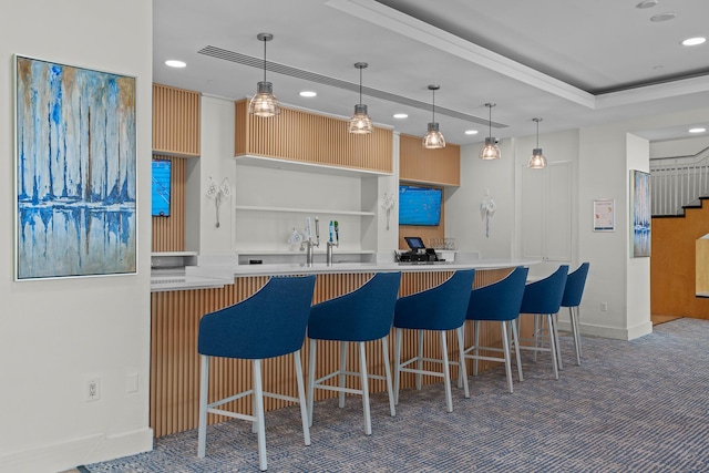 kitchen featuring a kitchen bar, light brown cabinetry, dark colored carpet, and hanging light fixtures