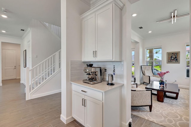 bar with white cabinetry, crown molding, and tasteful backsplash