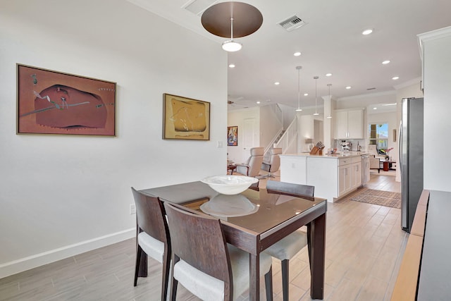 dining space with ceiling fan, ornamental molding, and light hardwood / wood-style flooring