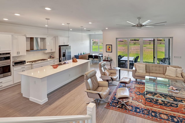 living room featuring ceiling fan, crown molding, and sink