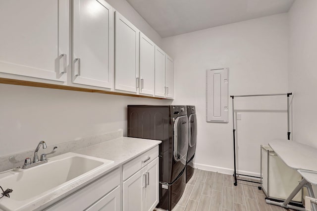 washroom with washing machine and dryer, cabinets, electric panel, and sink