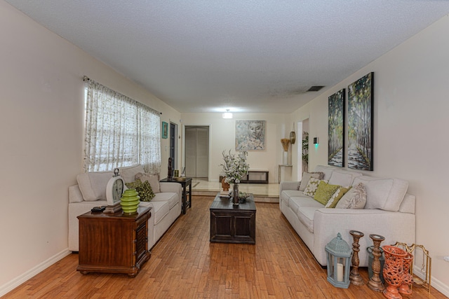 living room with a textured ceiling and light wood-type flooring