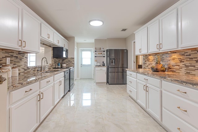 kitchen with light stone counters, sink, white cabinets, and stainless steel appliances