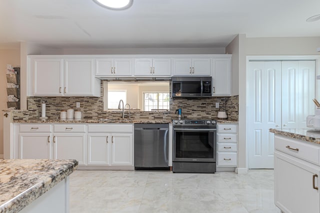 kitchen featuring white cabinetry, appliances with stainless steel finishes, backsplash, light stone counters, and sink