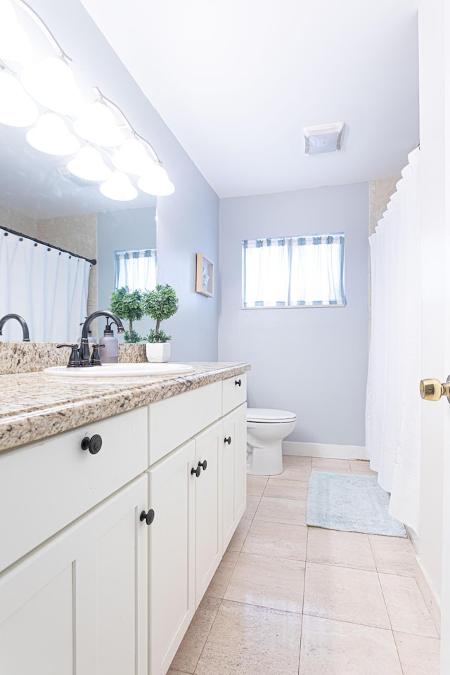 bathroom featuring toilet, a wealth of natural light, tile patterned flooring, and vanity