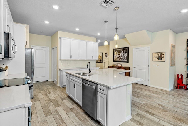 kitchen featuring sink, white cabinets, decorative light fixtures, a kitchen island with sink, and appliances with stainless steel finishes