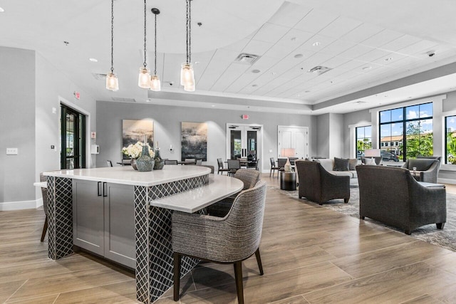 interior space featuring decorative light fixtures, a large island, a raised ceiling, and a kitchen breakfast bar