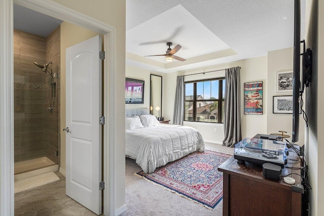 bedroom with a raised ceiling, a textured ceiling, and ceiling fan