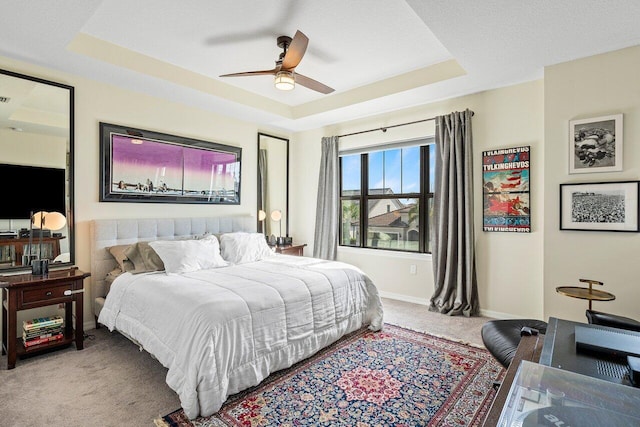 bedroom with a raised ceiling, ceiling fan, and light carpet