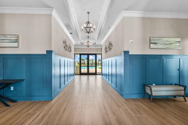 hallway with french doors, a notable chandelier, crown molding, and light hardwood / wood-style flooring