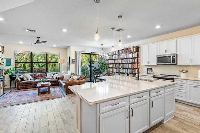 kitchen with sink, white cabinets, a kitchen island with sink, and appliances with stainless steel finishes