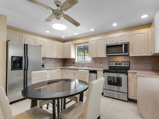 kitchen with light tile patterned floors, decorative backsplash, appliances with stainless steel finishes, ceiling fan, and sink