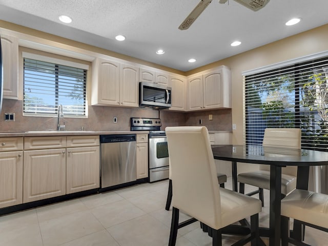 kitchen with stainless steel appliances, sink, ceiling fan, light tile patterned floors, and decorative backsplash