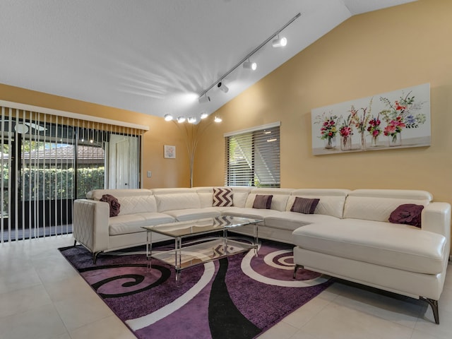 tiled living room featuring lofted ceiling and track lighting