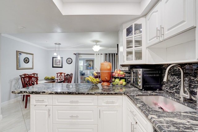 kitchen featuring dark stone countertops, white cabinets, decorative light fixtures, light tile patterned flooring, and sink