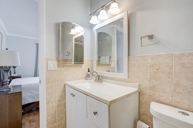 bathroom with toilet, vanity, tile walls, and ornamental molding