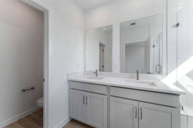 bathroom with toilet, hardwood / wood-style floors, vanity, and walk in shower