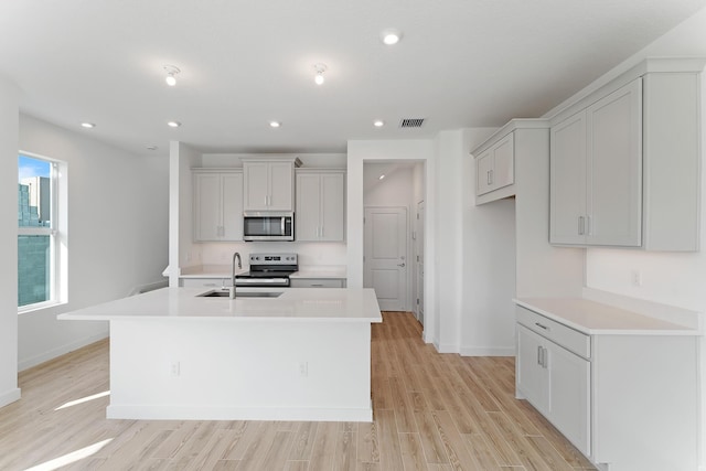 kitchen featuring light hardwood / wood-style floors, sink, a kitchen island with sink, and appliances with stainless steel finishes