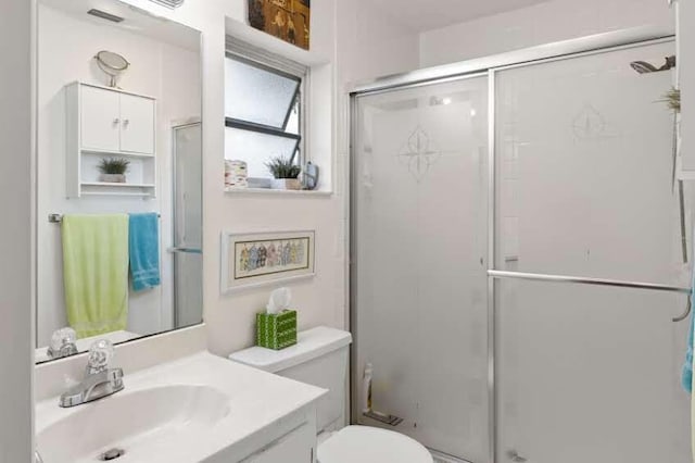 bathroom featuring toilet, vanity, and walk in shower